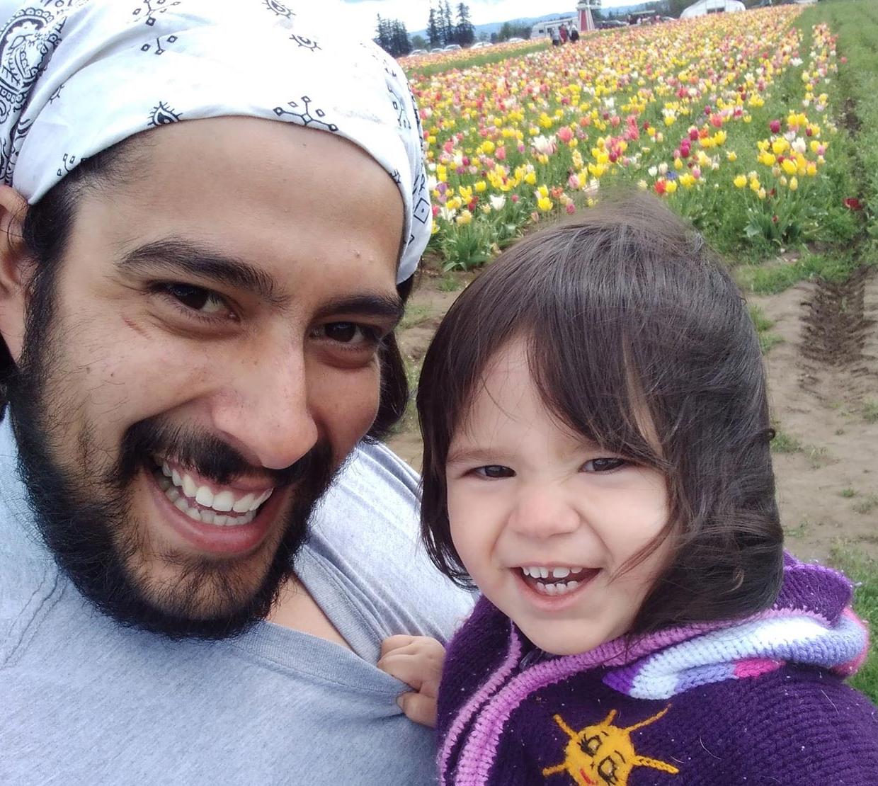 Oregon State physics graduate with daughter amid tulips.