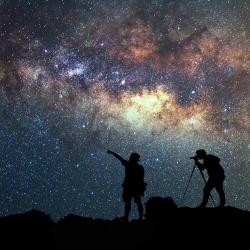 two silhouetted people watching the stars