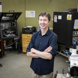 A man in a blue shirt stands in a laboratory.