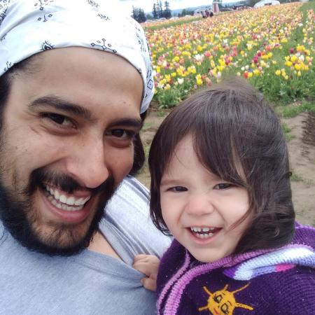 Oregon State physics graduate with daughter amid tulips.
