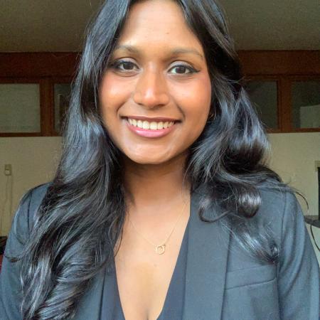 A smiling headshot of Sanjana Curtis in a blazer