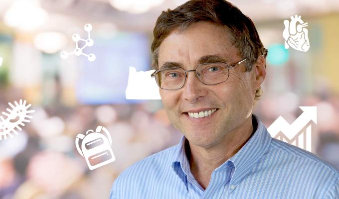 Carl Wieman in front of science major icons and audience