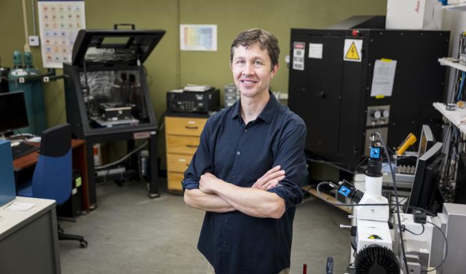A man in a blue shirt stands in a laboratory.